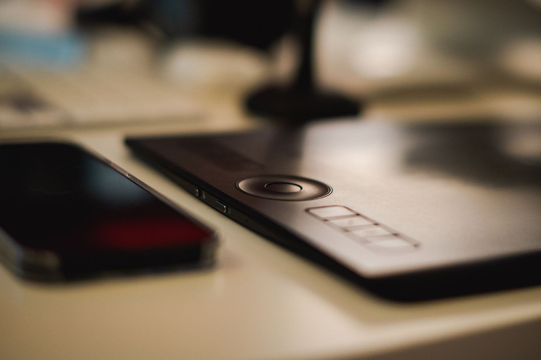 Close-up of a graphic tablet and smartphone on a designer's desk, emphasizing modern technology and creativity.