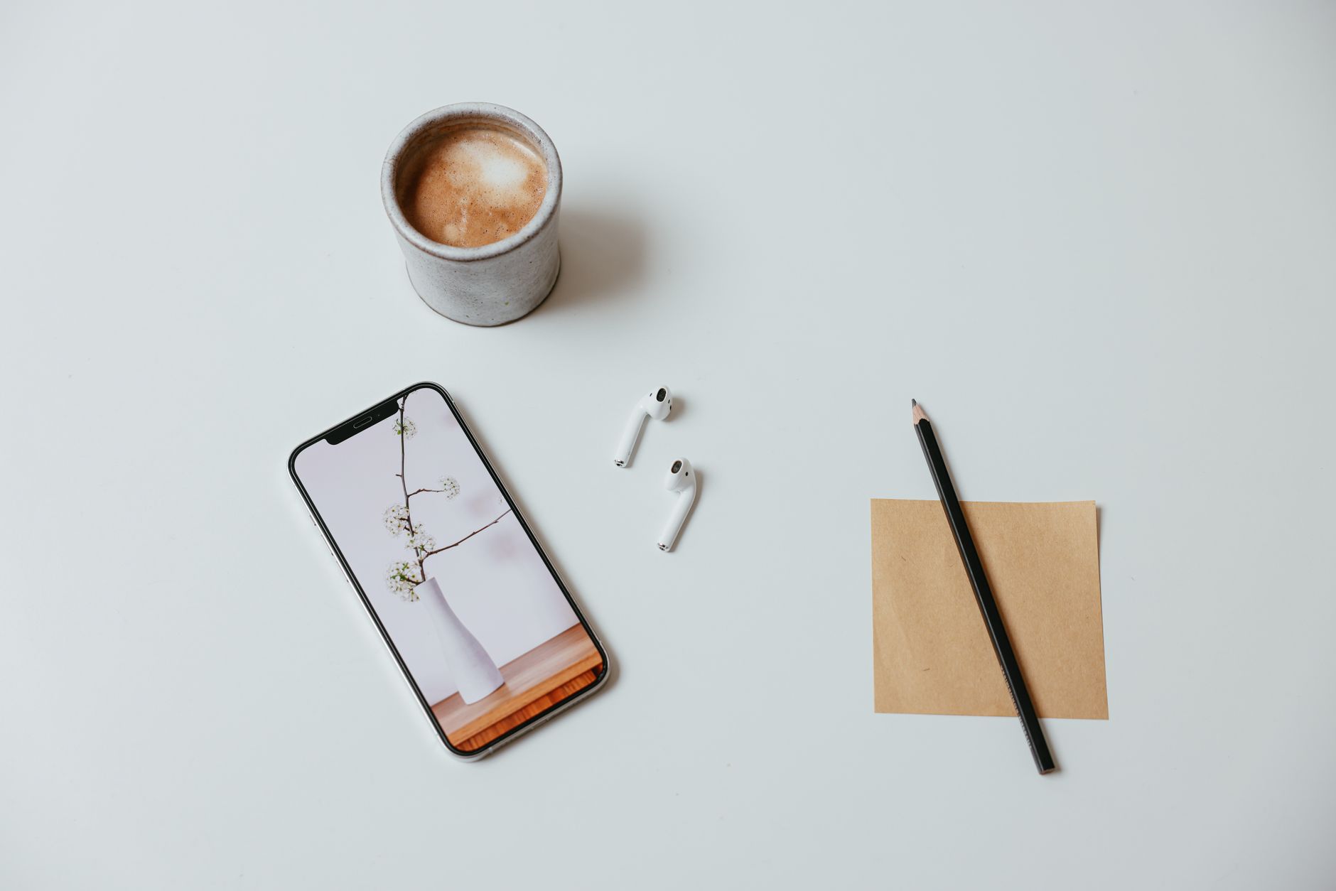 Minimalist flat lay featuring coffee, smartphone, and accessories.